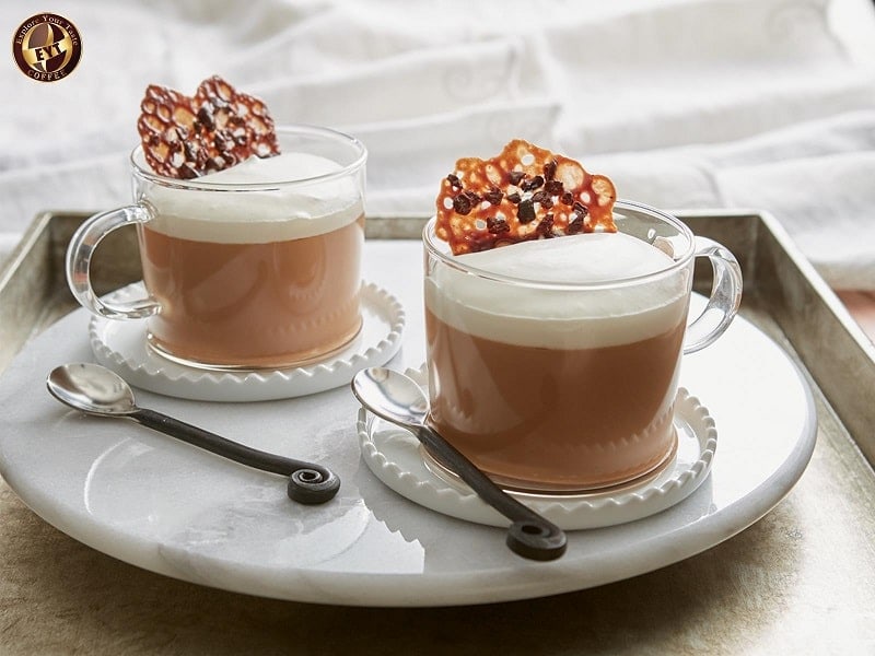 2. Đồ uống cà phê sữa hấp dẫn với bánh quy caramel trên bàn trà, hình ảnh thanh lịch tại EYT Coffee, quán cà phê phong cách hiện đại, phù hợp thưởng thức sáng hoặc chiều.